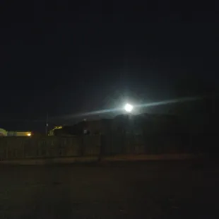 a street light at night with a fence in the foreground