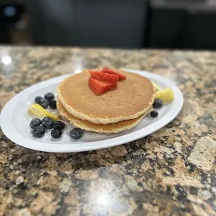 a plate of pancakes with strawberries and blueberries