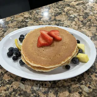 a plate of pancakes with strawberries and blueberries