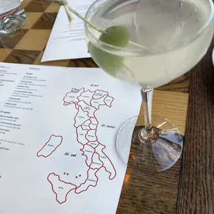 a glass of wine and a menu on a table