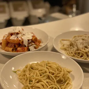 three plates of pasta on a counter