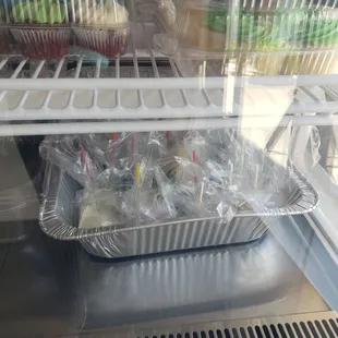 a tray of cupcakes in a display case
