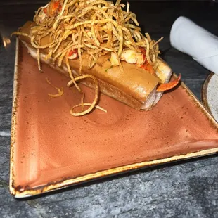 a hot dog with noodles on a plate