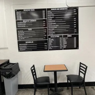 a table and two chairs in front of a menu board