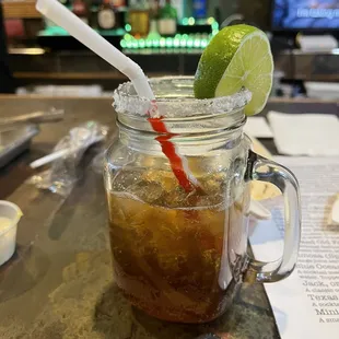 a drink in a mason jar with a straw and a lime slice