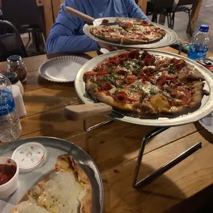 a man sitting at a table with two pizzas