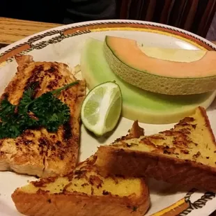 Baked salmon, fresh fruit and garlic toast.