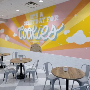 tables and chairs in front of a mural