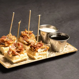 Try our Mini Texas Bites! Mini waffles topped with a chicken tender and sweet candied bacon drizzled with powdered sugar!