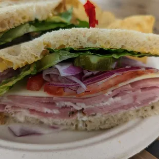 Ham and Swiss cheese sandwich with mustard, mayonnaise, lettuce, tomato, onion, and pickles.