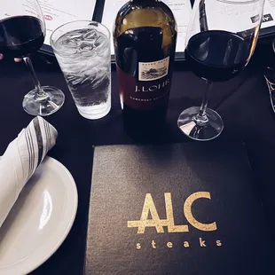 a table with a menu and wine glasses