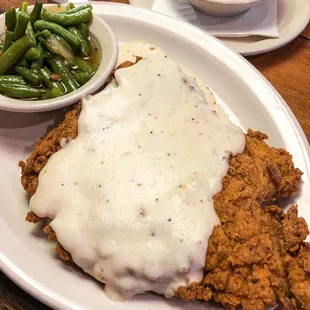 a plate of fried chicken with gravy and green beans