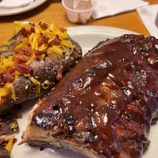 a plate of ribs and baked potatoes