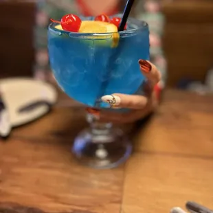 a woman holding a blue cocktail