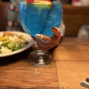 a hand holding a blue drink