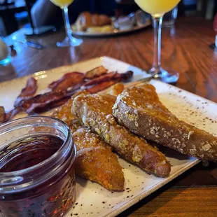a plate of french toast, bacon, and orange juice