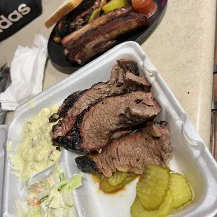 Brisket, cole slaw, potato salad (front)  Sliced brisket sandwich and pork ribs (back)