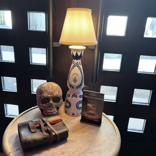 a table with a lamp and a skull