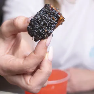 a person holding a piece of bbq