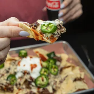 a hand holding a piece of nachos