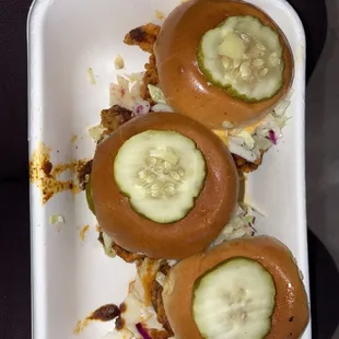 three buns with pickles on them