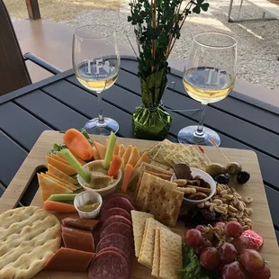 a platter of cheese, crackers, grapes, and salami