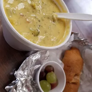 Broccoli and cheddar soup with little bits of bacon, accompanied by a fresh croissant and grapes.