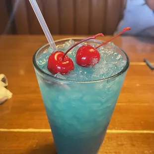 a blue drink with two cherries in it