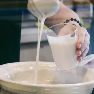a person pouring milk into a bowl