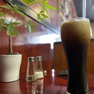 a tall glass of dark beer on a table