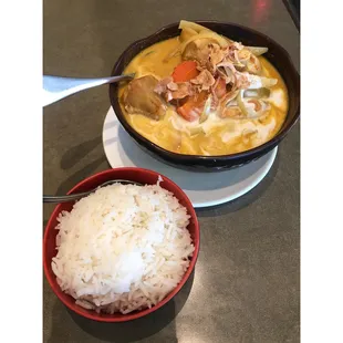 Yellow chicken curry with onions, carrots, and lots of potatoes, and a bowl of jasmine rice on the side.