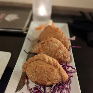 three pastries on a plate with a knife