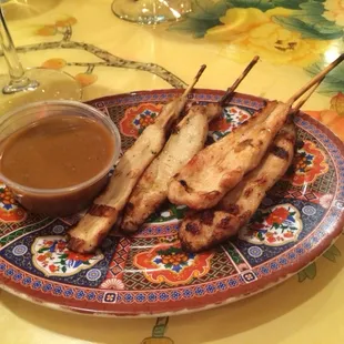 a plate of skewered meat and sauce
