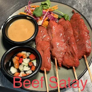 a plate of meat satay with dipping sauce
