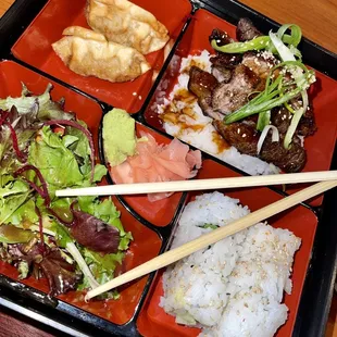 a bento box of food with chopsticks