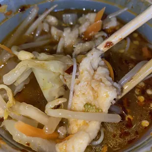 a bowl of soup with chopsticks