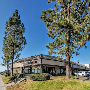 the outside of a restaurant with trees in the foreground