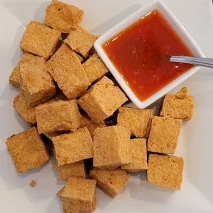 a plate of tofu cubes with dipping sauce