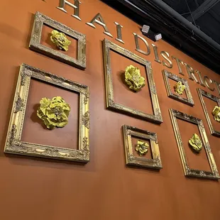 a wall with a variety of gold frames