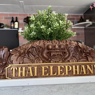 a wooden sign with a plant in it