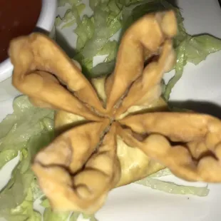 a plate of fried food with lettuce and dipping sauce