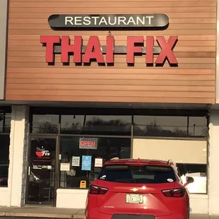 a red car parked in front of a restaurant