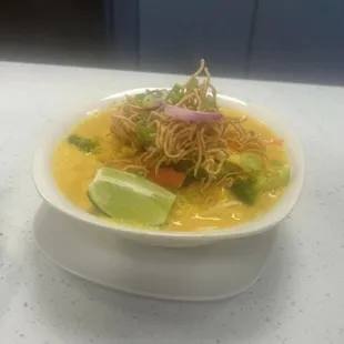 a bowl of soup with a lime wedge