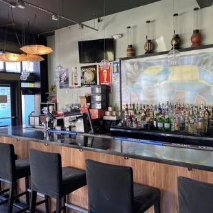 a bar with black chairs and a painting on the wall