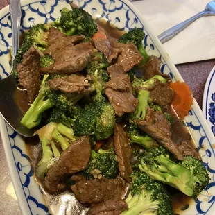 beef and broccoli on a blue and white plate