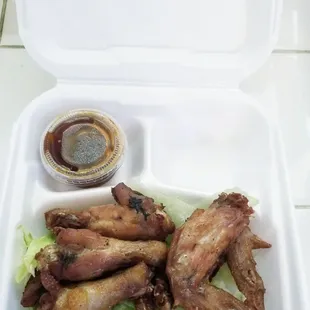 chicken wings and lettuce in a styrofoam container