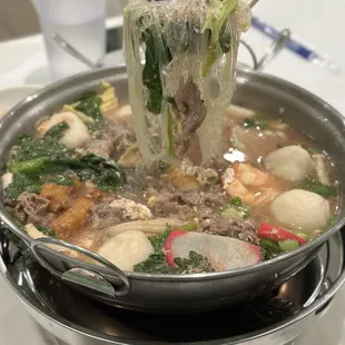 a ladle of noodles being lifted from a pot