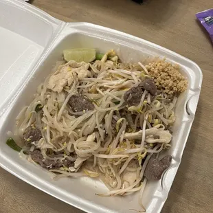 a plate of noodles and meat in a styrofoam container