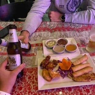 a person sitting at a table with a plate of food and a bottle of beer