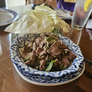 NEAU NAM TOK [GL] Grilled marinated thinly-sliced steak. Seasoned with mint leaves, scallion, hot peppers, and fresh lime juice.